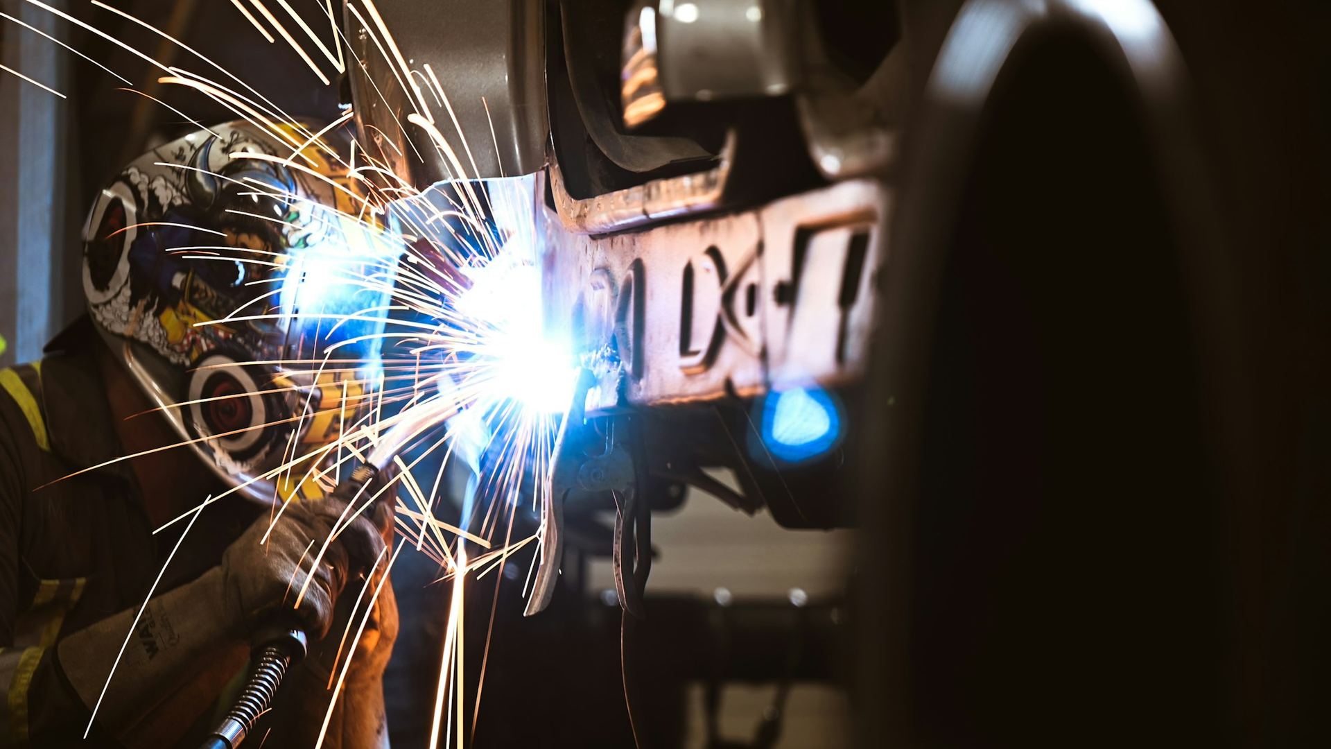 Welder working on a vehicle chassis with sparks flying